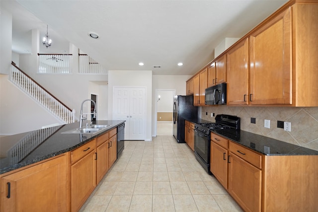 kitchen with decorative backsplash, a chandelier, dark stone counters, black appliances, and sink