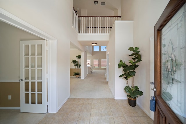 entryway featuring light colored carpet and a towering ceiling