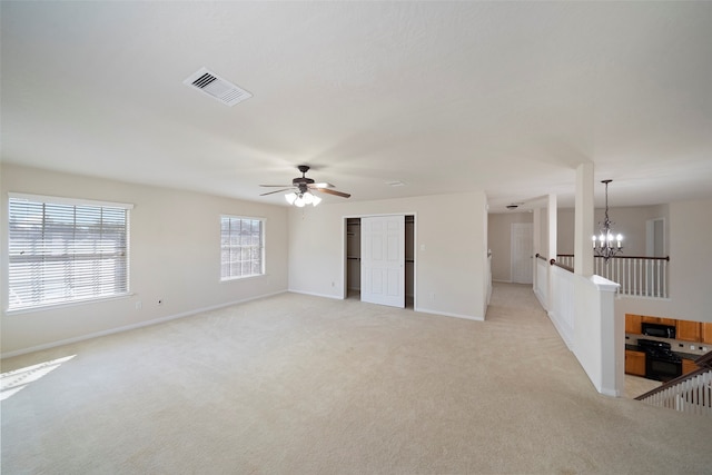 spare room featuring light carpet and ceiling fan with notable chandelier