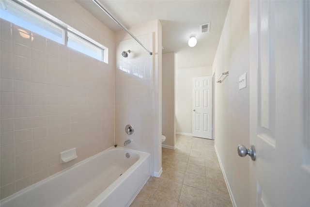 bathroom featuring toilet, tiled shower / bath combo, and tile patterned floors