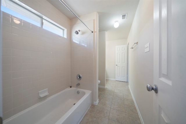 bathroom with toilet, tiled shower / bath, and tile patterned floors