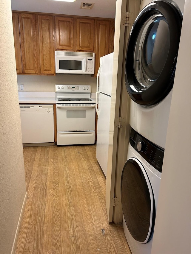 2207 S Braeswood S Unit 42E, Houston, TX 77030 - kitchen featuring white appliances, stacked washer / dryer, brown cabinets, and light wood-style floors