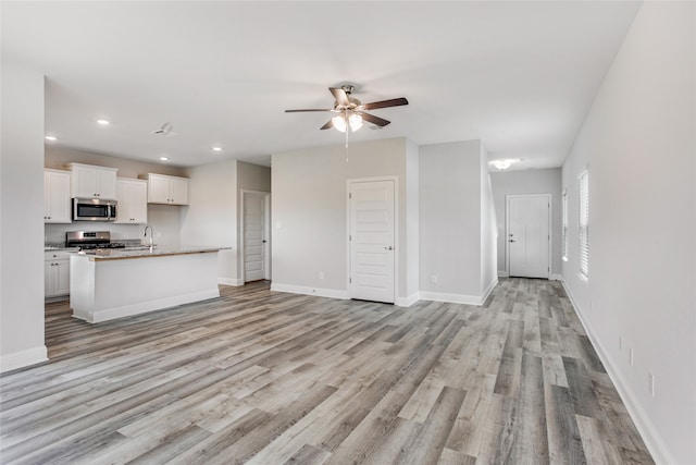 unfurnished living room featuring light wood-type flooring, sink, and ceiling fan