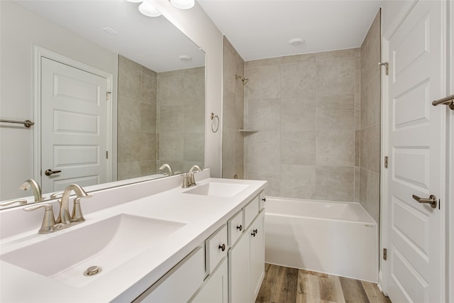 bathroom with wood-type flooring, tiled shower / bath, and vanity