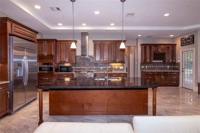 kitchen featuring sink, an island with sink, hanging light fixtures, wall chimney exhaust hood, and stainless steel appliances