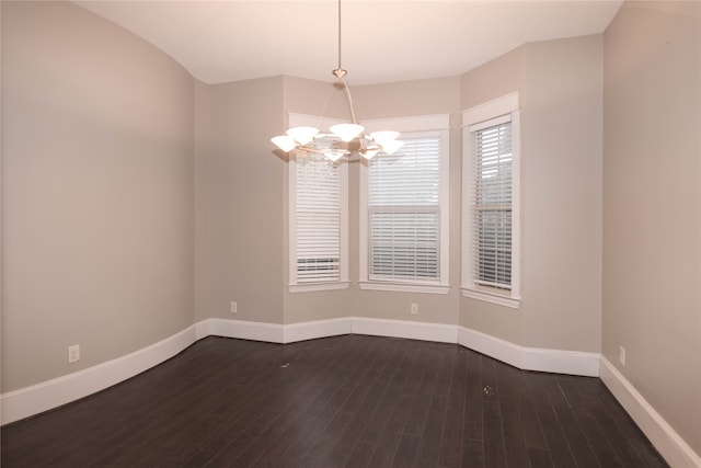 unfurnished room featuring an inviting chandelier and dark hardwood / wood-style floors