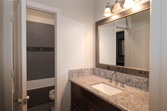 bathroom with a tile shower, vanity, and toilet