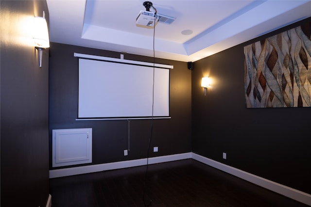 cinema room with a tray ceiling and dark wood-type flooring