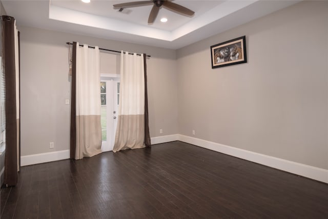 unfurnished room with ceiling fan, a raised ceiling, and dark hardwood / wood-style floors