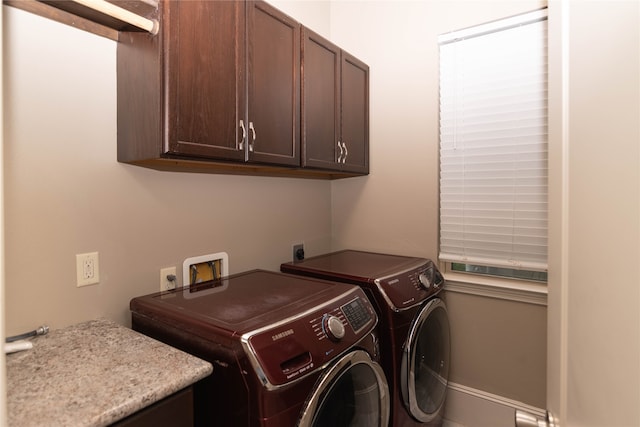 clothes washing area with cabinets and washing machine and clothes dryer