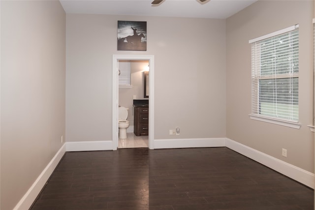 unfurnished bedroom with ceiling fan, ensuite bathroom, and dark hardwood / wood-style flooring