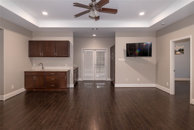 kitchen featuring dark brown cabinets, dark hardwood / wood-style floors, sink, a raised ceiling, and ceiling fan