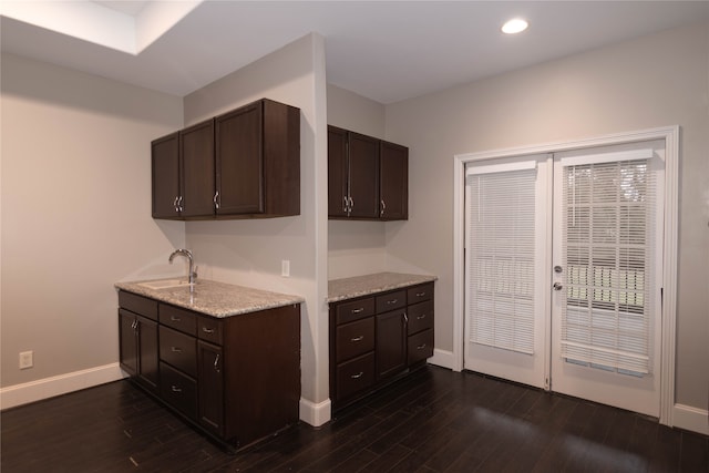 kitchen with dark brown cabinetry, sink, light stone countertops, and dark hardwood / wood-style flooring