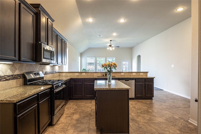 kitchen featuring appliances with stainless steel finishes, vaulted ceiling, backsplash, kitchen peninsula, and a center island