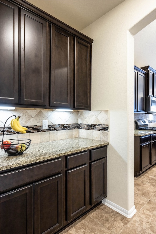 kitchen featuring light stone countertops, dark brown cabinetry, and tasteful backsplash