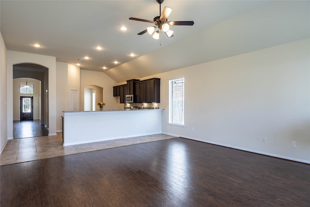 unfurnished living room with ceiling fan, lofted ceiling, and dark wood-type flooring