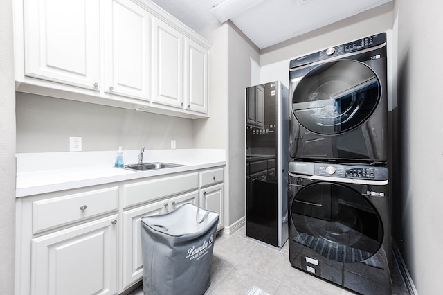 laundry room featuring light tile patterned floors, cabinets, sink, and stacked washing maching and dryer