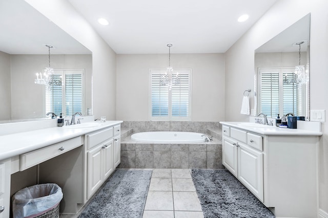 bathroom with a healthy amount of sunlight, tiled bath, and vanity