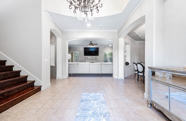 tiled foyer entrance with ceiling fan with notable chandelier and ornamental molding