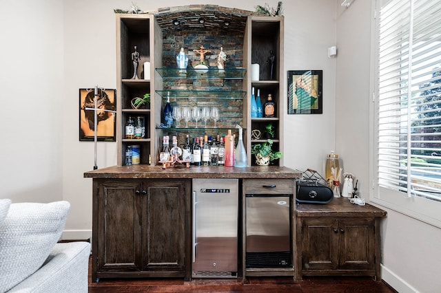 bar featuring dark brown cabinetry and dark hardwood / wood-style flooring