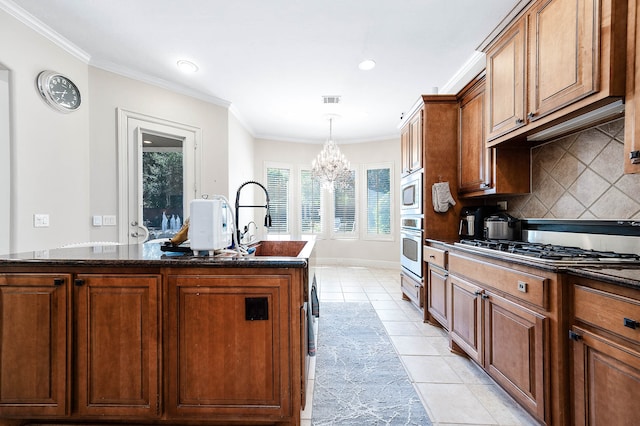 kitchen with a notable chandelier, light tile patterned flooring, a kitchen island with sink, and crown molding