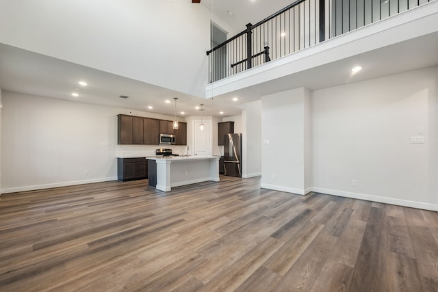 unfurnished living room featuring hardwood / wood-style flooring and a towering ceiling