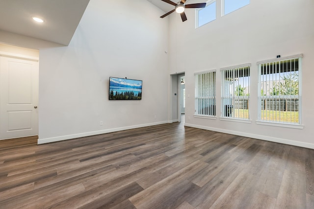 unfurnished living room with ceiling fan, dark wood-type flooring, and a high ceiling