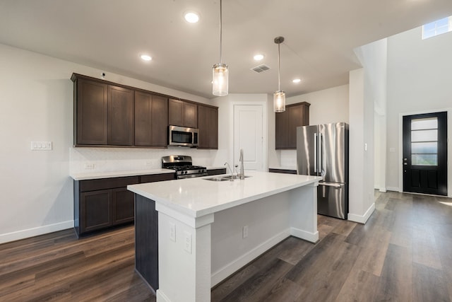 kitchen with pendant lighting, sink, a kitchen island with sink, appliances with stainless steel finishes, and dark hardwood / wood-style flooring