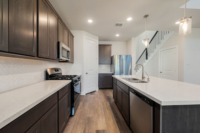 kitchen with pendant lighting, dark hardwood / wood-style floors, sink, stainless steel appliances, and backsplash