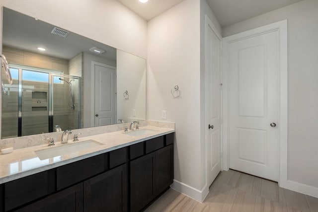 bathroom with a shower with shower door and vanity