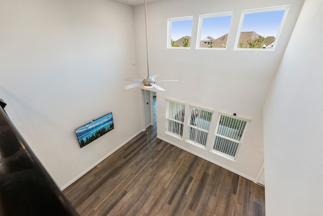 living room with ceiling fan, dark hardwood / wood-style flooring, and a high ceiling