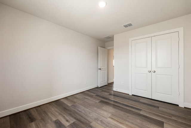 unfurnished bedroom with a closet and dark hardwood / wood-style flooring