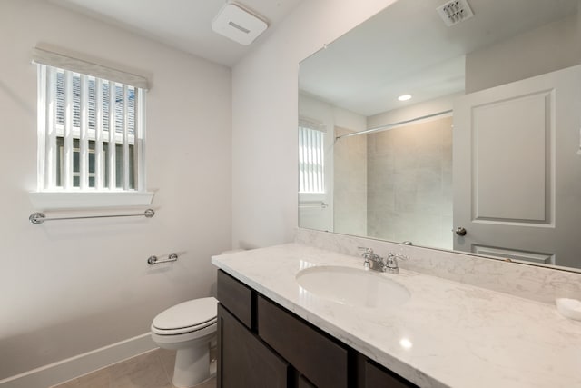 bathroom featuring a tile shower, tile patterned flooring, vanity, and toilet