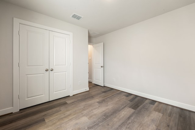 unfurnished bedroom with a closet and dark wood-type flooring