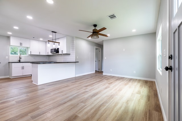 unfurnished living room with sink, light hardwood / wood-style flooring, and ceiling fan