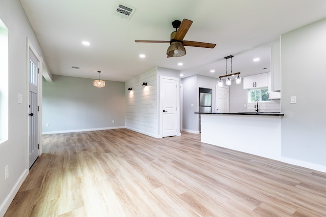 unfurnished living room with ceiling fan, light wood-type flooring, and sink