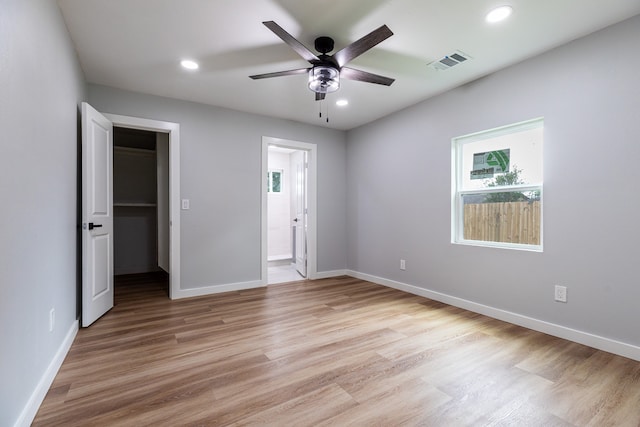 unfurnished bedroom with ceiling fan, light wood-type flooring, a closet, and a walk in closet