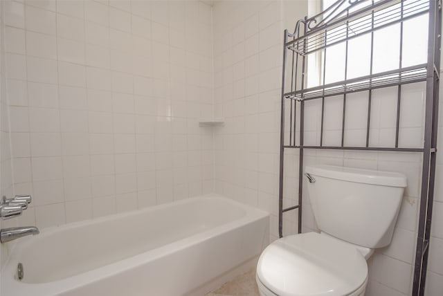 bathroom with tile walls, washtub / shower combination, and toilet