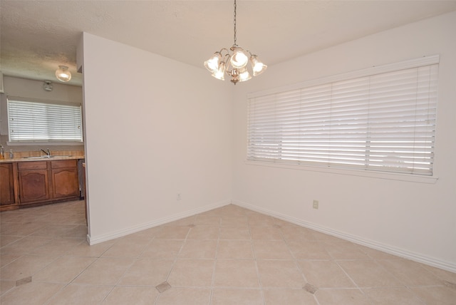 spare room featuring sink, a chandelier, a textured ceiling, and light tile patterned floors