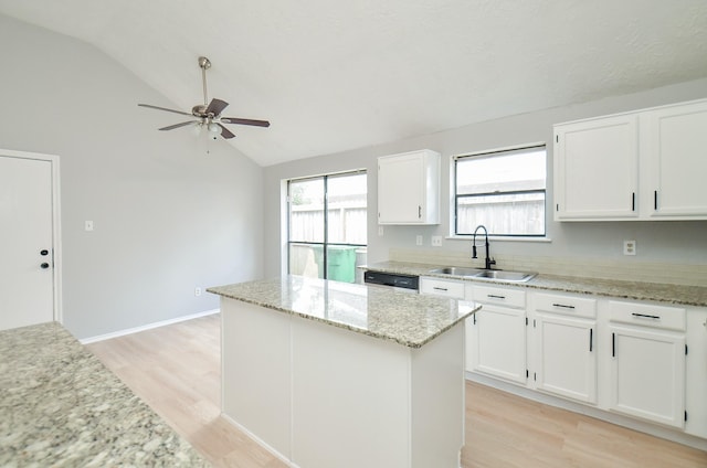 kitchen with lofted ceiling, sink, light stone countertops, a kitchen island, and white cabinetry