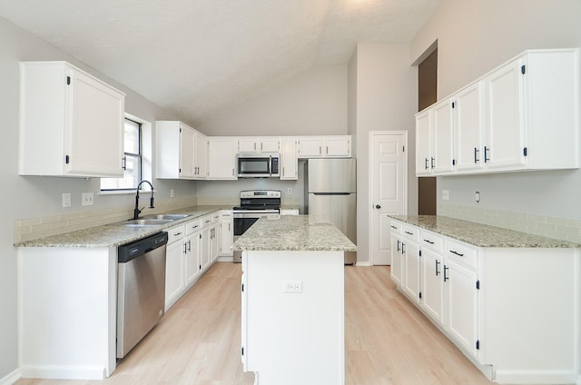 kitchen featuring light stone countertops, appliances with stainless steel finishes, white cabinetry, and a kitchen island