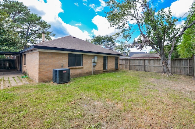 back of house featuring central AC unit and a lawn