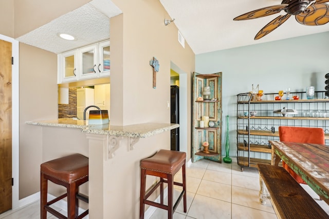 bar with light tile patterned flooring, light stone countertops, a textured ceiling, and white cabinetry