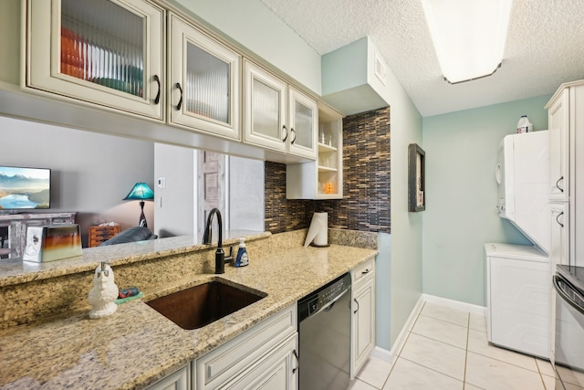 kitchen featuring sink, cream cabinets, a textured ceiling, appliances with stainless steel finishes, and light stone countertops