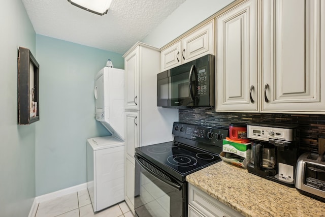 kitchen with light tile patterned floors, a textured ceiling, backsplash, stacked washing maching and dryer, and black appliances