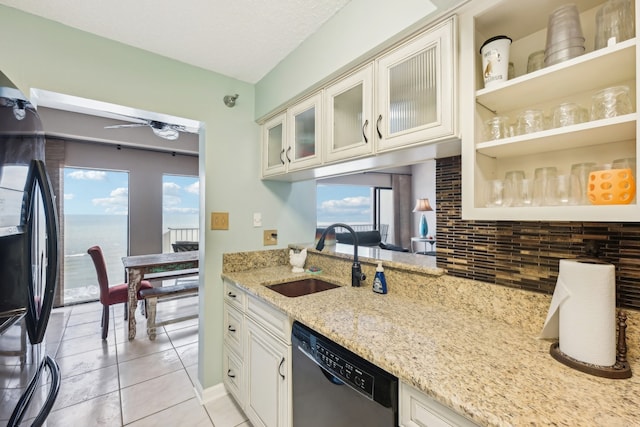 kitchen featuring a water view, black refrigerator, sink, light stone countertops, and stainless steel dishwasher