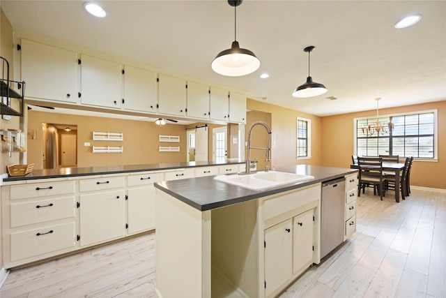 kitchen featuring dishwasher, sink, an island with sink, hanging light fixtures, and light hardwood / wood-style flooring