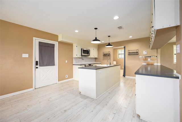 kitchen with sink, light hardwood / wood-style flooring, decorative light fixtures, white cabinetry, and a center island