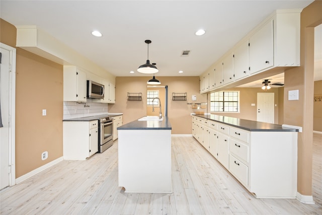 kitchen with pendant lighting, stainless steel appliances, light hardwood / wood-style floors, and white cabinetry