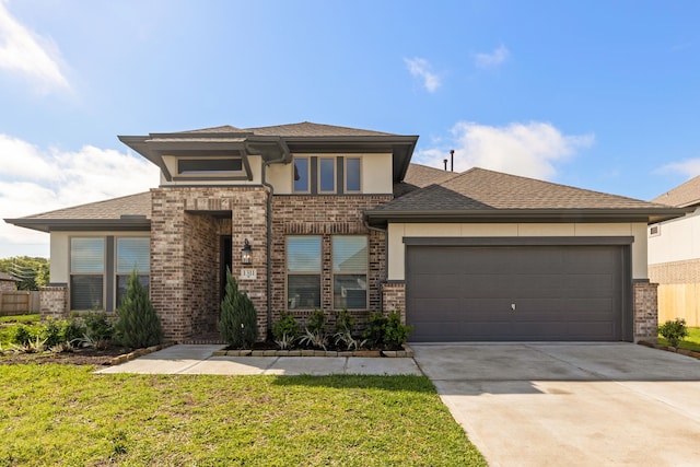 prairie-style home featuring a garage and a front lawn